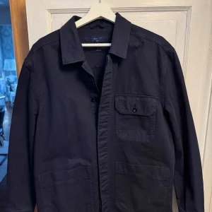 Mörkblå overshirt från Gant - Snygg mörkblå overshirt från Gant med klassisk krage och knappar framtill. Passar för alla tillfällen! Använd cirka fem gånger