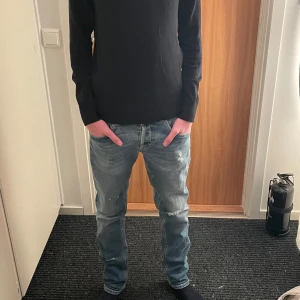 Dondup jeans med slitningar - Snygga blå jeans med slitningar och en klassisk femficksdesign. De har en slim passform och är perfekta för att lyfta en outfit. Som man kan se på sista bilden så har en av bält öglorna lossnat på den nedre delen, vilket man varken tänker på när man själv har på sig jeansen eller ser från någon annans perspektiv. Va inte rädd att fråga eller att be om fler bilder på vad som