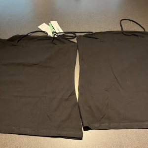 Svart långärmad topp från Gina Tricot - Säljer två svarta långärmade toppar från Gina Tricot i storlek XL. Perfekt basplagg för garderoben. Topparna är enkela och stilrena, vilket gör dem lätta att matcha med andra kläder.