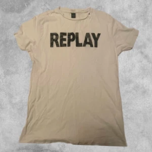 Vit t-shirt från Replay - Säljer en vit t-shirt från Replay med stort svart tryck på framsidan. T-shirten är kortärmad och har en klassisk rund halsringning. Perfekt för en avslappnad stil.