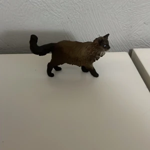 Schleich hund - En liten brun kattfigur med detaljerad päls och svans. Perfekt för samlare eller som dekoration.
