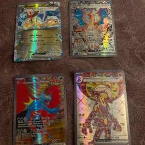 Pokémon-kort med Dragonite ex, Charizard ex, Roaring Moon ex och Toxtricity ex - Säljer en samling av fyra Pokémon-kort: Dragonite ex, Charizard ex, Roaring Moon ex och Toxtricity ex. Korten har en holografisk yta och visar detaljerade illustrationer av Pokémon-karaktärerna. Perfekt för samlare eller spelentusiaster!