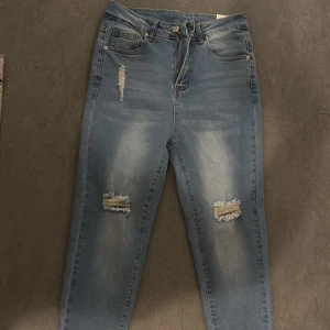 Blå jeans med slitningar från Shein - Snygga blå jeans från Shein med slitningar på låren och vid anklarna. De har en klassisk femficksdesign och knappgylf. Perfekta för en avslappnad stil. Aldrig använt
