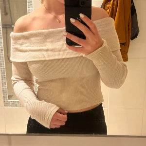 Beige offshoulder ribbad tröja - Beige offshoulder tröja med ribbad struktur från Ginatricot. Använd ett fåtal gånger. Storlek M men skulle säga att den passar en S också.
