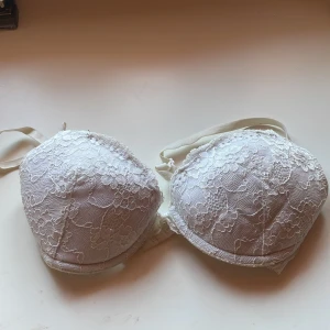 Vit spets-bh från H&M - Säljer en elegant vit bh från H&M med vacker spetsdetalj. Den har justerbara axelband och en bekväm passform. Perfekt för att känna sig extra fin till vardags eller speciella tillfällen.