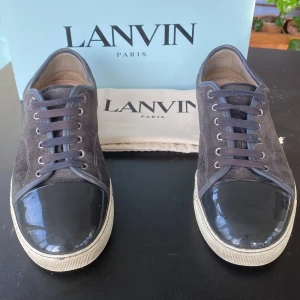 Lanvin - Hej säljer dessa fetta grå-bruna skorna från Lanvin med en kombination av mocka och glansigt material på tån. Skorna har snörning och en vit sula som ger en stilren look. Perfekta för en trendig och avslappnad stil. Skorna är självfallet ÄKTA då de finns allt og. Box,dustbag och kvitto. Kan byttas mot ex Louboutin.