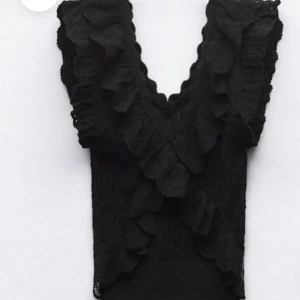 Svart spetsblus med volang - Elegant svart blus i spets med volangdetaljer framtill. Den är nästan aldrig använt och är så gott som ny, helt slutsåld!