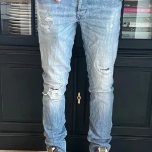 Blå slitna jeans - Säljer ett par blå jeans med slitningar på knäna och låren. De är Slim fit. De har riktigt sköna slitningar och lite stänk av kvarg😁De är storlek 28/32