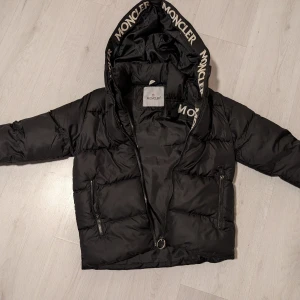 Svart dunjacka  - Snygg svart dunjacka. Använt en säsong, väldig fin skicka utom slitage som syns i två sista bilder. Inga håll, inga fläckar. 138-140cm