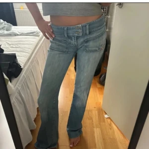 Lågmidjade bootcut jeans diesel  - Snygga ljusblå bootcut jeans med låg midja och dubbla knappar fram. Perfekta för en avslappnad stil. Klassisk femficksdesign och lätt slitna detaljer för en trendig look.