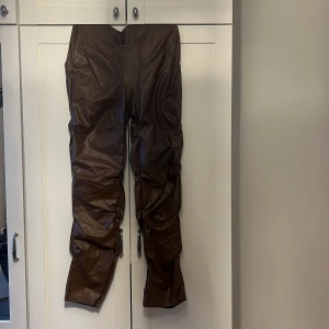 Bruna skinnbyxor - Snygga bruna skinnbyxor i en loose passform. Perfekta för en cool och edgy look. Byxorna har en hög midja och är tillverkade i ett mjukt skinnmaterial som ger en lyxig känsla.