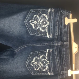 Blå ND weekend jeans med broderade bakfickor - Snygga blå jeans med broderade bakfickor.Liknar Miss Me jeans. I bra skick, endast lite slitna längst ner på ena benet bak. Stl 10 inköpta i USA och stl motsvarar ca 40/42