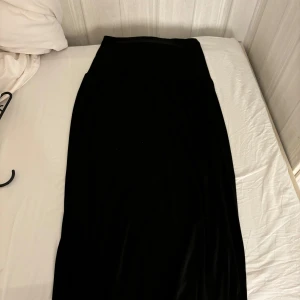 Svart långkjol från 157 - Elegant svart långkjol från 157 i storlek XS. Perfekt för en stilren look med sin enkla design och långa längd. Kjolen är lätt att matcha med olika toppar och accessoarer.