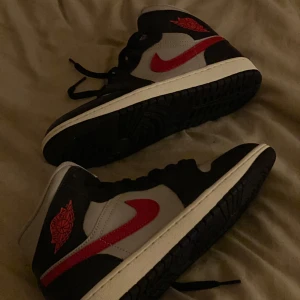 Nike Air Jordans i svart, grått och rött - Snygga Nike Air Jordans i en stilren färgkombination av svart, grått och rött. Skorna har en klassisk design med snörning och en röd Nike-logga på sidan Använda Max 3 ggr. Köpta från Zalando 