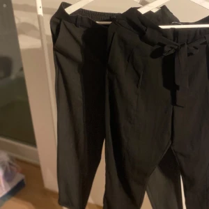 Svarta byxor från Vero Moda - Snygga svarta byxor från Vero Moda med elastisk midja och knytband framtill. Byxorna har en stilren design med raka ben och diskreta fickor bak. Perfekta för en chic och bekväm look.
