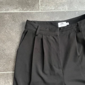 Svarta kostymbyxor - Hoss x Nakd, stl 36 - Säljer dessa svarta kostymbyxor från NA-KDs kollektion med Hoss. Byxorna har highwaist, wide leg och är i storlek 36. Längd 114 cm, innerbenslängd 82 cm & midja 36 cm