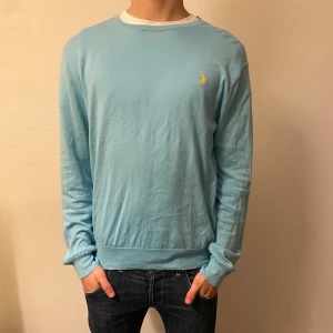 Ljusblå tröja från Polo Ralph Lauren - Säljer en stilren ljusblå tröja från Polo Ralph Lauren med det klassiska broderade logotypen på bröstet. Storlek L. Modellen har storlek M därför ser den lite större ut. Tröjan har en slim fit passform och långa ärmar, perfekt för en avslappnad men ändå elegant look. Bra skick dock lite uttöjd!