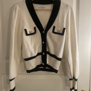 Vit kofta från Holly & Whyte - Snygg vit kofta från Holly & Whyte (Lindex egna märke)  med svarta detaljer. Super söt och använd 1-2 gånger. 