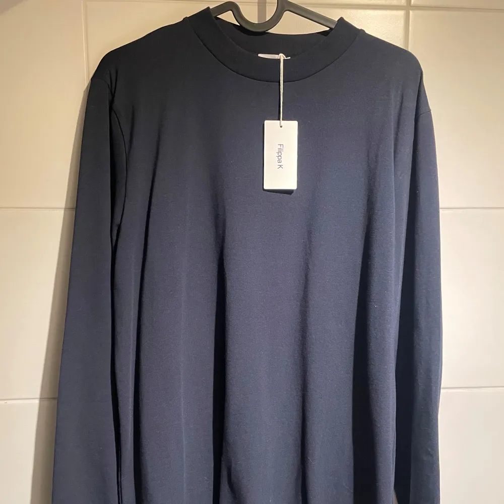 Snygg och stilren marinblå långärmad herrtröja från Filippa K. Tröjan har  en rund halsringning och är i ett mjukt material. Helt ny/oanvänd med prislapp kvar. Storlek S, normal i storlek. . Neuletakit & Villapaidat.