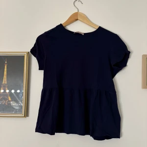 Blå blus med korta ärmar - Snygg svart blus med korta ärmar och en lös passform. Perfekt för både vardag och speciella tillfällen. Blusen har en enkel design med en rund halsringning. STORLEK PETITE alltså passar kortare människor 