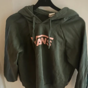 Grön hoodie från Vans - Säljer en snygg grön hoodie från Vans med rosa logga på bröstet. Perfekt för en avslappnad stil med sin bekväma passform och justerbara huva.