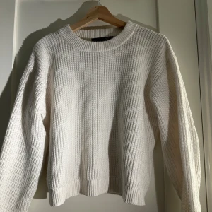 Vit stickad tröja - Säljer en stilren vit stickad tröja med rund hals och långa ärmar. Perfekt för kyligare dagar och enkel att matcha med olika outfits. Tröjan har en klassisk design med ribbade kanter.