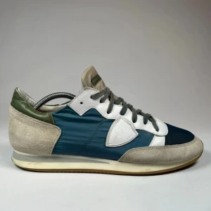 Snygga sneakers i mocka ifrån Philippe model  - Stilrena sneakers med en mix av blå, vit och grön färg. Skorna har en snygg kombination av mocka och syntetmaterial med snörning framtill. Perfekta för en avslappnad stil. Köpte för 3800kr och säljer nu för 1600kr 9/10 i skick använda fåtal gånger. Skriv om ni är intresserade!!