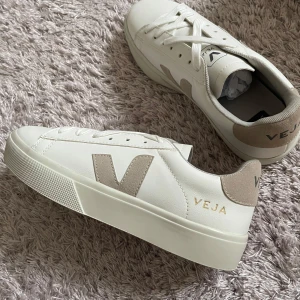 Vita sneakers från Veja - Snygga vita sneakers från Veja med beige detaljer och snörning. Skorna har en stilren design med märkets logga på sidan och hälen. Perfekta för en avslappnad stil.
