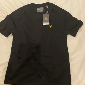 Svart Lyle & Scott T-shirt  - Svart tränings T-shirt från Lyle & Scott i storlek S. Skick 10/10 eftersom den aldrig är använd och endast testad.                                      Nytt pris: 400kr Mitt pris: 199kr