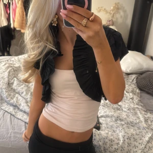 Svart bolerotopp - Snygg svart bolerotopp med volangdetaljer. Perfekt för att lägga till en extra touch till din outfit!!💕