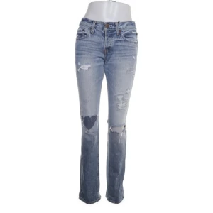 Ljusblå jeans med slitningar från Hollister - Snygga ljusblå jeans från Hollister med slitningar på knäna och låren. De har en klassisk femficksdesign och en knappgylf. Perfekta för en avslappnad stil.