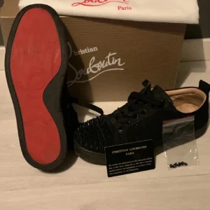 Svarta sneakers från Christian Louboutin - Snygga svarta sneakers från Christian Louboutin med den ikoniska röda sulan. Skorna har snörning och är dekorerade med spetsiga detaljer på ovansidan. Perfekta för att ge en lyxig touch till din outfit. Billigt pris på av lite slitet på undersidan. Strl 39 men passar 40-41