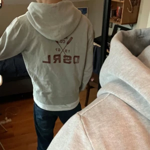 Hoodie från Ralph Lauren - En grå zip hoodie från Denim & Supply Ralph Lauren med skönt tryck på bröstet. Storlek M men passar mer som S/XS. Bra skick men dragtappen saknas men själva dragkedjan fungerar. Hör av er vid frågor!