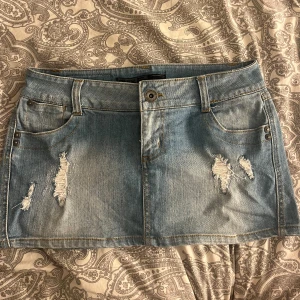 Lågmidjad jeanskjol från ONLY - Superfin blå lågmidjad minikjol från ONLY med slitna detaljer. Storlek W27. Midjemått: 36cm. Mycket bra skick då den knappt använts. Skriv för  frågor eller fler bilder 💗