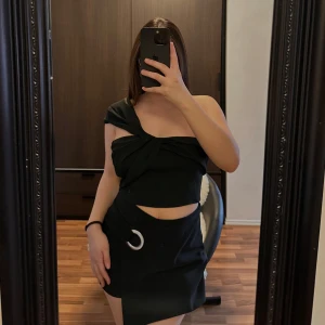 Topp - Snygg svart oneshoulder topp med knytdetalj framtill. Perfekt för en stilren och modern look. Toppen har en dragkedja bak för enkel på- och avtagning.🥰🥰🥰