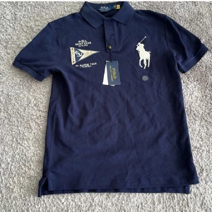 Ralph Lauren Polo tröja - Snygg mörkblå pikétröja från Polo Ralph Lauren med broderad logga och textdetaljer. Tröjan har en klassisk krage och knappar framtill. Storlek S. Perfekt för en stilren look. Pris går att diskutera vid affär.