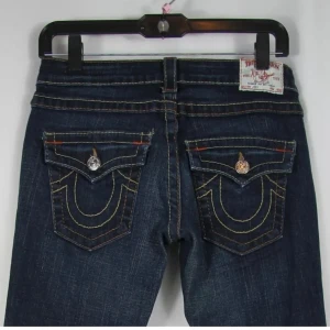 Lågmidjade mörkblå utsvängda jeans från True Religion - Snygga mörkblå jeans från True Religion med hästsko bakfickor och kontrastsömmar. Säljer för att dom tyvärr blivit för små för mig. Jättefint skick!! *Bilder från tidigare säljare*  