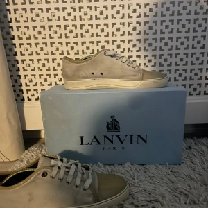  sneakers från Lanvin - Snygga grå sneakers från Lanvin med klassisk design och snörning. Skorna har en stilren look med en vit sula som ger en fräsch kontrast. Perfekta för en avslappnad och trendig stil.