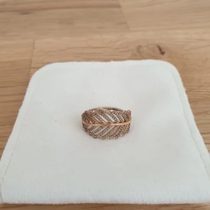 Roseguld Pandora ring - Shimmering Feather Ring. Ring från Pandora i roseguld, i använd skick. Mer info:  https://sg.pandora.net/en/rings/rings/statement-rings/shimmering-feather-ring/180886CZ.html