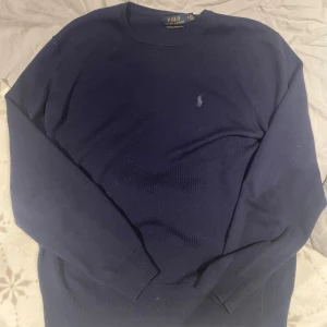 Ralph lauren tröja - Säljer en stilren mörkblå tröja från Polo Ralph Lauren i tvättbar merinoull. Tröjan har en klassisk design med rund hals och långa ärmar. Perfekt för en elegant och avslappnad look. Det är merino ull och tröjan har nypris över 2000kr. Sparsamt använd och inga defekter. 