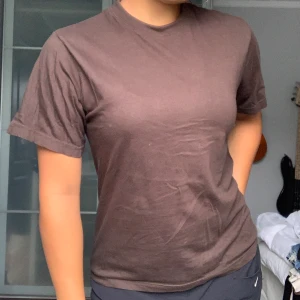 Brun t-shirt från Baz - Säljer en enkel och stilren brun t-shirt från Baz. Den är kortärmad och har en normal passform, perfekt för vardagsbruk. Materialet känns mjukt och bekvämt.