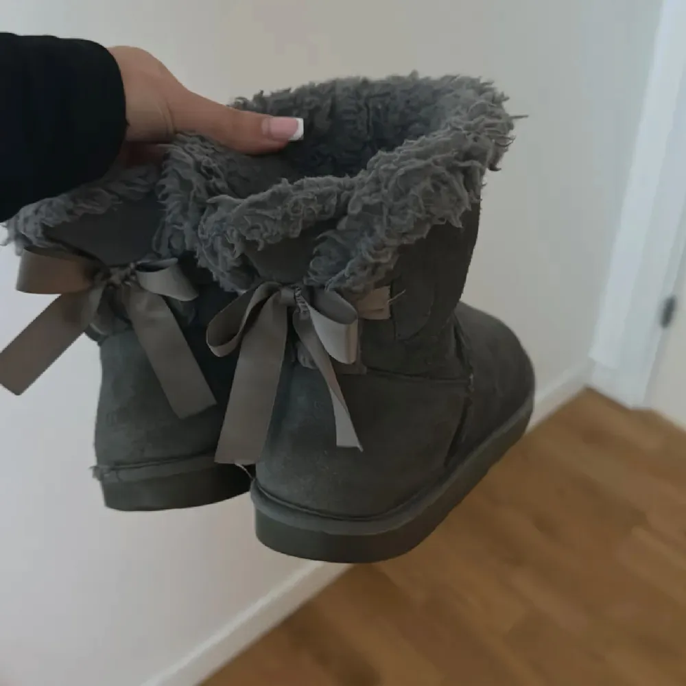 Jättesöta gråa uggs med rosetter som inte kommer till användning i storlek 38.. Skor.