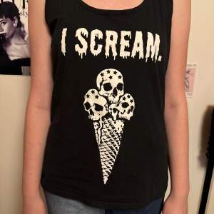 Coolt svart linne från emp med trycket 'I Scream' i vit text. Designen har en unik illustration av glass med dödskallar. Perfekt för en avslappnad och edgy stil. Linnet är ärmlöst och gjort i mjukt bomullsmaterial.