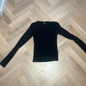 Svart tajt urringad tröja  - Svart långärmad ribbad tröja med urringning 