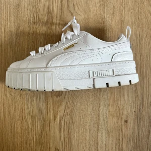 Vita sneakers från Puma - Säljer ett par snygga vita sneakers från Puma i storlek 38. Skorna har en chunky sula och klassisk snörning. De är i nyskick och perfekta för både vardag och fest. Passar till alla outfits och ger en cool touch till din stil!