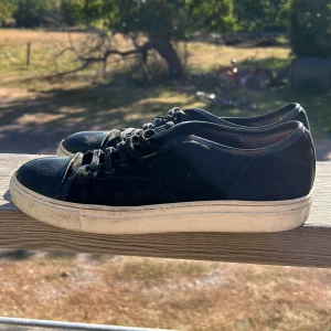 Svarta sneakers i mocka - Säljer ett par svarta sneakers i mocka med vit sula. De har snörning och är i bra skick, perfekta för vardagsbruk. Passar till både jeans och mer uppklädda outfits.