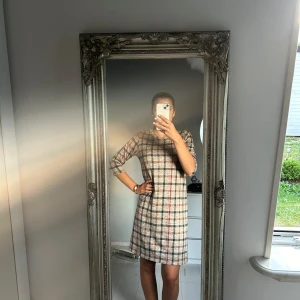 Superfin klänning med rutmönster och kortare ärmar.  - Klänning med rutmönster. Har använts ett fåtal gånger bara. Funkar perfekt nu inför hösten och kallare dagar. Superfin tillsammans med tex höga boots🤩