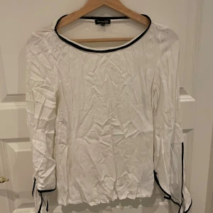 Vit långärmad topp från Massimo Dutti - Säljer en stilren vit långärmad topp från Massimo Dutti. Den har svarta detaljer längs halsringningen och ärmsluten, vilket ger en snygg kontrast. Perfekt för både vardag och festliga tillfällen!