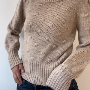 Beige stickad tröja - Säljer en supermysig beige stickad tröja med ett diskret prickigt mönster. Tröjan har långa ärmar och ribbstickade muddar vid ärmslut och nederkant. Perfekt nu till höst och vinter🍁🍁❄️❄️ är i storlek XS men sitter som en S