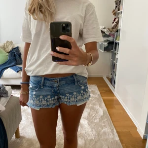 Hollister shorts  - Säljer dessa lågmidjade jeans shorts från hollister med broderade blommor  Midjemått: 39 cm